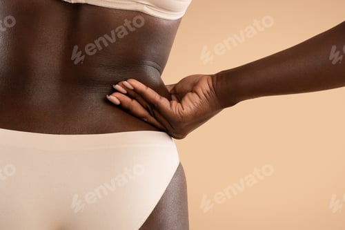Preview: Back view of black woman pulling skin on her sides