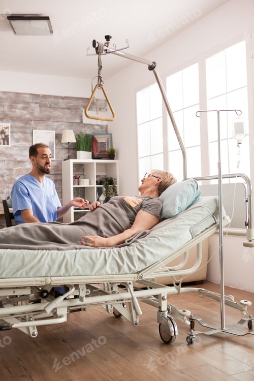 Preview: Caregiver Comforting Senior Woman Lying in Hospital Bed