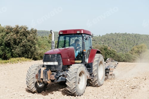 Preview: Young woman driving tractor and working a field on sunny day