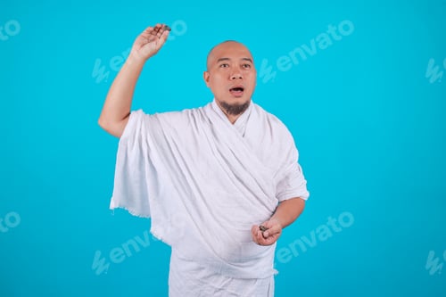 Preview: Muslim Pilgrim in White Ihram Holding Small Stones and Gesturing to Throw Them