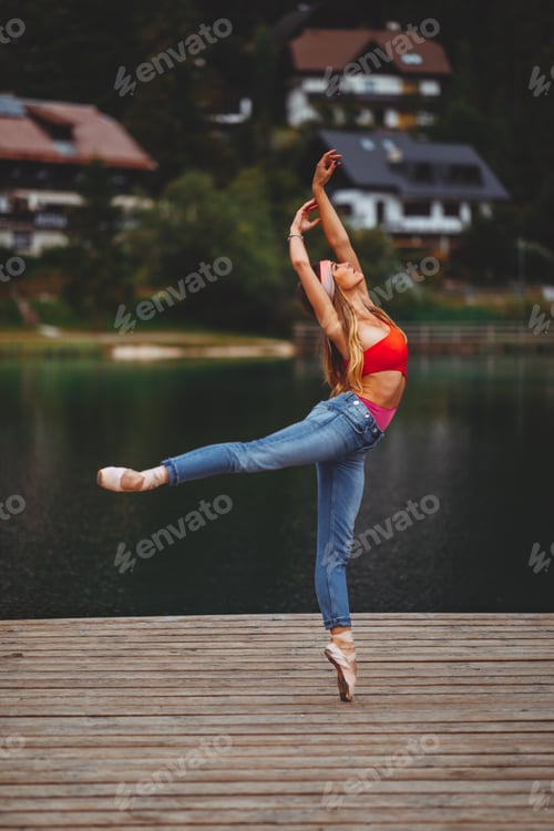 Preview: Attractive young woman dancing on the dock next to the lake