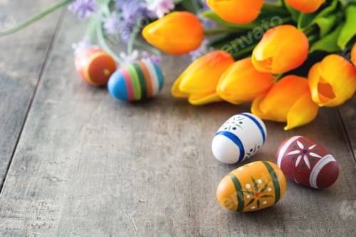 Preview: Colorful easter eggs and orange tulips decorating rustic wooden table