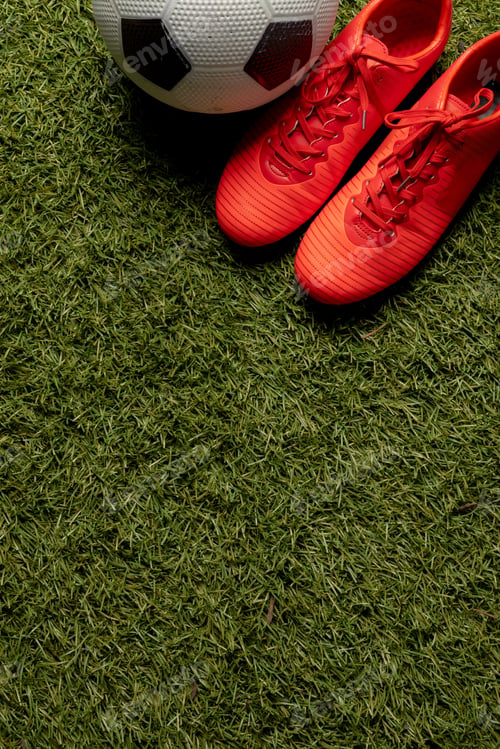 Preview: Composition of football and shoes over sports stadium and copy space