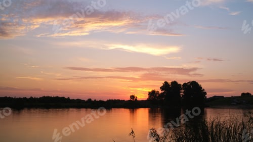 Preview: Colorful summer sunset on the river bank.Natural landscape. Reflection, blue sky and yellow sunlight