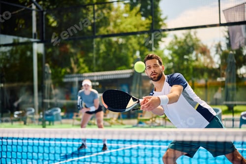 Preview: Young athletic man playing padel on outdoor tennis court.