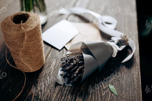 Preview: A little bouquet of flowers packed in dark paper, postcard, envelope, bobbin of twine and white