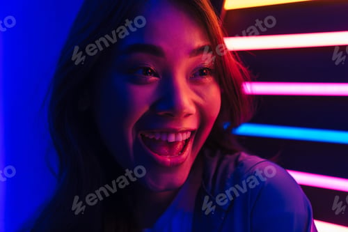 Preview: Surprised positive woman posing over neon lights.