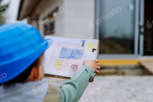 Preview: LIttle boy with drawn picture in front of their unfinished house.