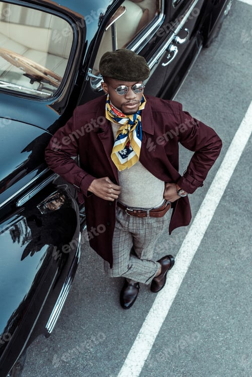 Preview: Stylish african american man posing in front of a car with hands on waist