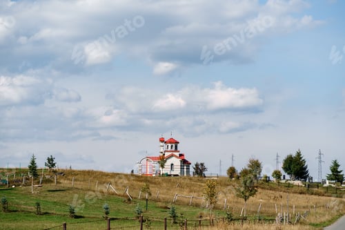 Preview: White brick church with red roof in the field