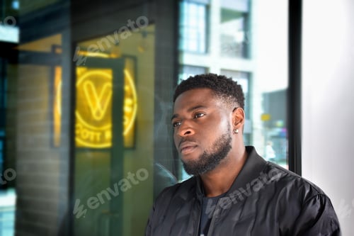 Contemplative Man Standing Beside Glass Storefront