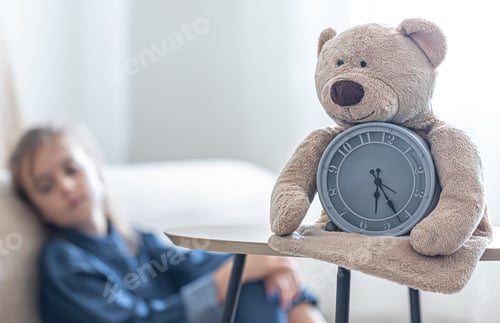 Preview: Teddy bear with alarm clock on a blurred background of the children's room.
