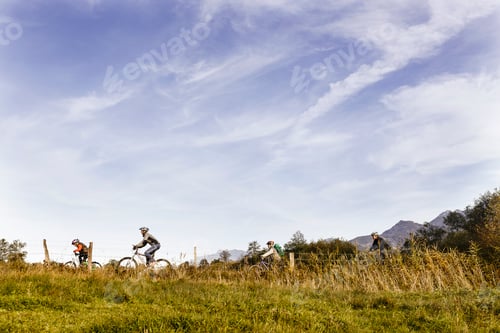 Preview: Cyclists enjoying a ride through scenic countryside beneath a vast, cloudstreaked sky.