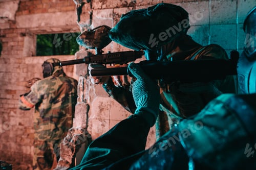 Preview: partial view of paintball team in uniform and protective masks playing paintball with marker guns in