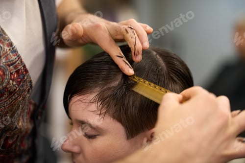 Preview: Hairdresser combing wet hair of young woman in salon