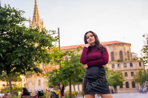 Preview: Portrait of a brunette woman with a leather skirt next to a church visiting the city, lifestyle