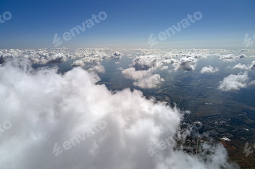Preview: Aerial view from airplane window at high altitude of earth covered with white puffy cumulus clouds.