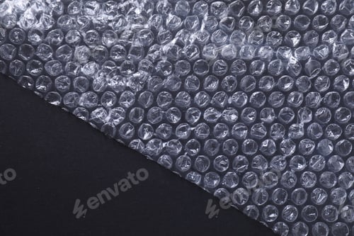 Preview: Transparent bubble wrap on black background, top view. Space for text