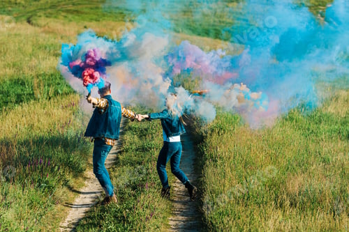 Preview: back view of couple holding colorful smoke bombs in rural field