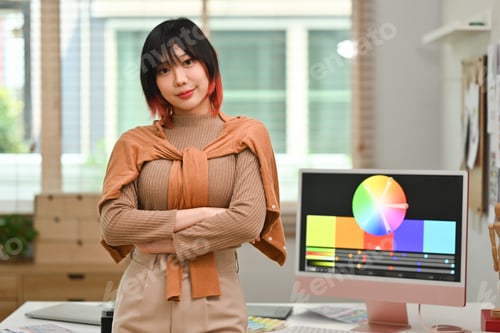 Preview: Portrait of young stylish designer with a lovely smile standing in front of a table in modern office