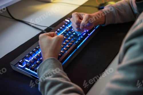 Preview: Caucasian man using the keyboard of his gamer computer with LED lights and playing games