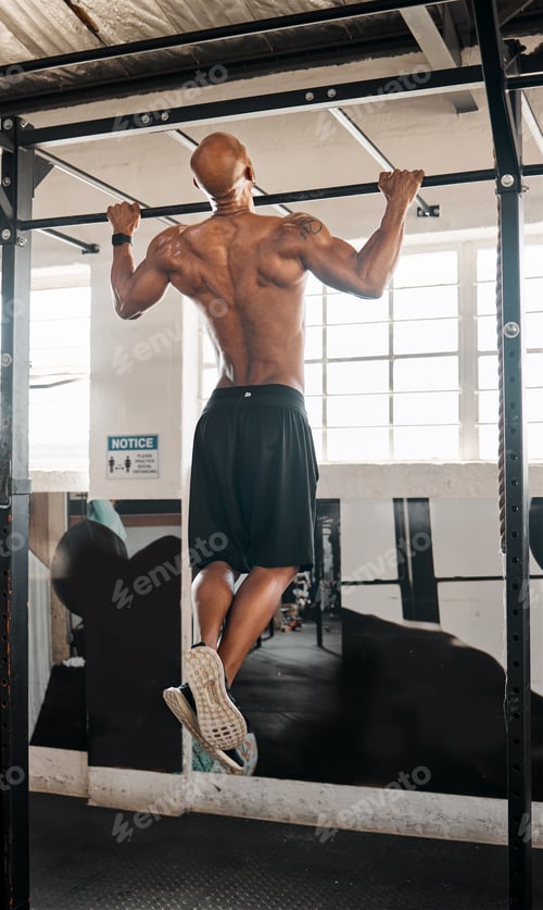 Preview: Focus on the body you aim to have. Shot of a man completing pull ups in his gym.