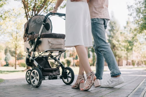 Preview: cropped image of parents walking with baby carriage in park