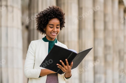 Preview: Afro businesswoman holding clipboard outdoors at the street.