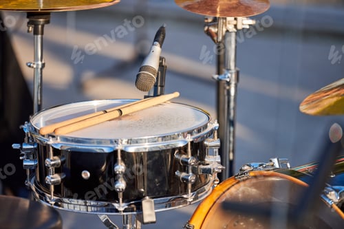 Preview: Drum kit at outdoor rock party close up, drumsticks on tom-tom drum at summer outdoor rock party