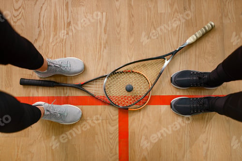 Preview: Female players legs and squash rackets, top view