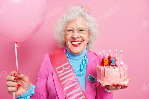 Preview: Special occasion age and festivity concept. Happy smiling wrinkled senior woman holds festive strawb