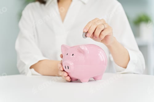 Preview: A woman putting money into a pig piggy bank