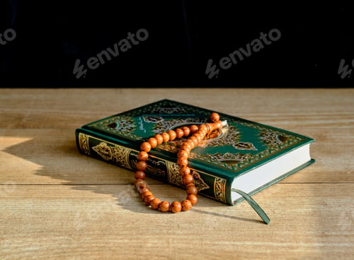 Preview: A green and gilded book of Quran and a rosary