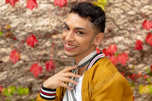 Preview: Portrait of happy biracial transgender man looking at camera, with rocks and leaves in background
