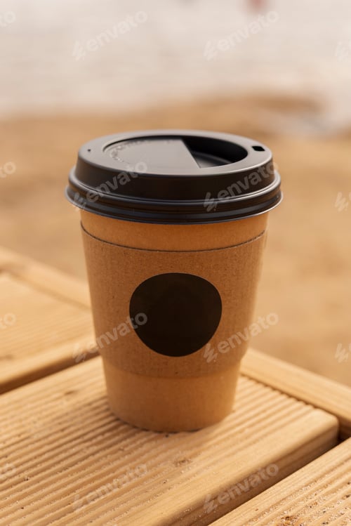 Preview: A cup of warm beverage sits on a wooden table near the shore. The sandy beach and calm water