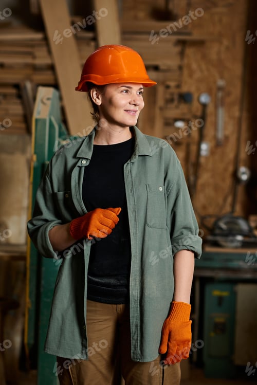 Preview: A skilled female carpenter smiles while crafting wood in her vibrant workshop space