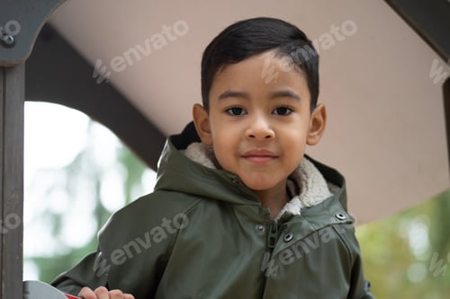 Preview: Low angle view close up portrait of happy young latin boy in a park at winter