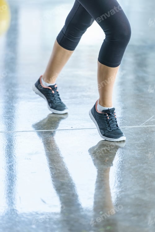 Preview: low section of sportswoman in sportswear and sneakers in sports center