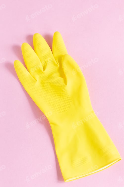 Preview: Vertical closeup shot of a yellow plastic glove on a pink background