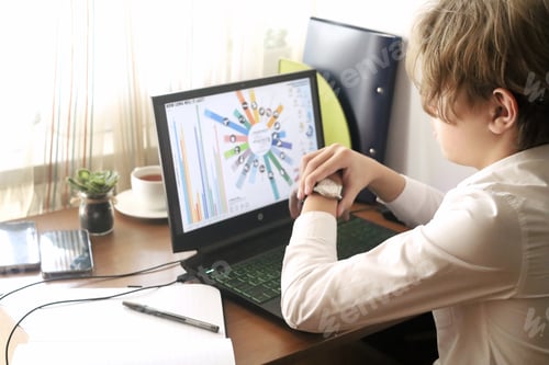 Preview: A young businessman sits in front of his laptop, studying the stock market and looking at his watch