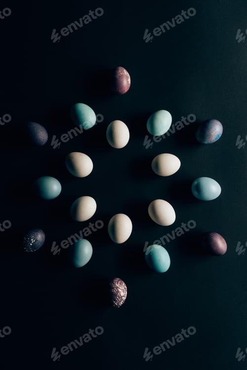 Preview: flat lay of colored painted easter eggs on dark surface