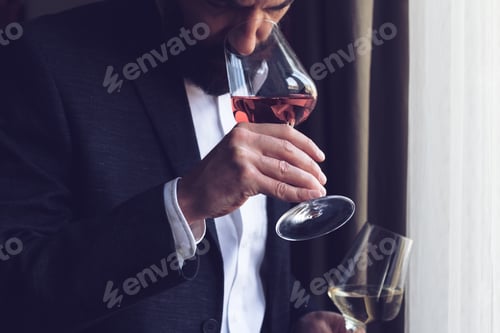 Preview: man tasting a glass of rose wine