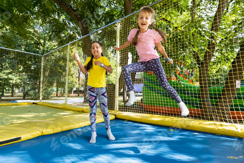 Preview: two young active girls doing exercises for squatting with trampoline