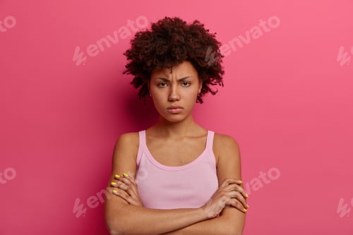 Vista previa: Portrait of dissatisfied insulted dark skinned woman crossed arms over body, looks in displeasure, s