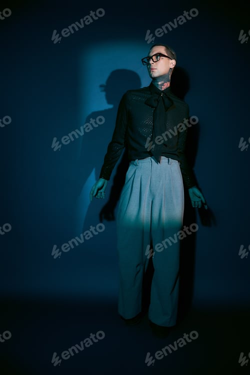 Preview: Elegant young man showcases modern fashion in dramatic lighting against a deep blue backdrop