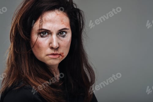 Preview: a battered woman in black clothes on an isolated gray background. Violence against women