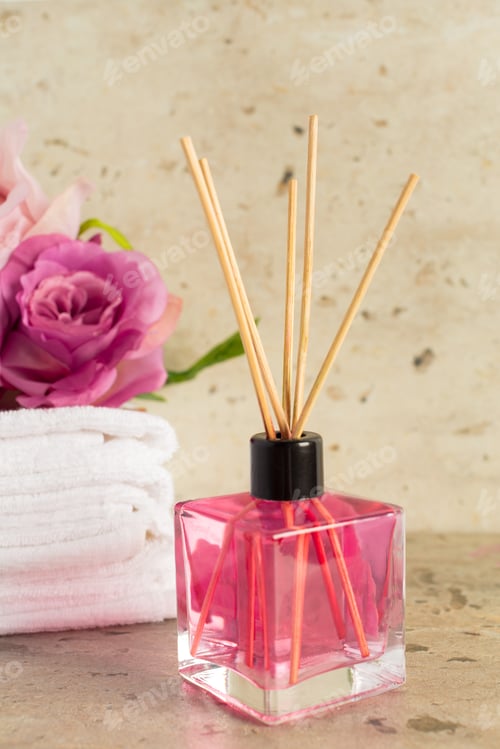 Preview: Decorative pink diffuser with flower arrangement and towels in a serene setting