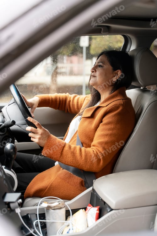 Preview: Mature Asian female driver driving car at the way of work. Modern people and transport concept