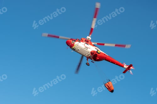 Preview: Red helicopter flying above with empty Bambi bucket