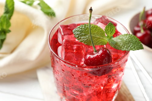 Preview: Tasty cherry soda with ice cubes, berries and mint in glass on white wooden table, closeup